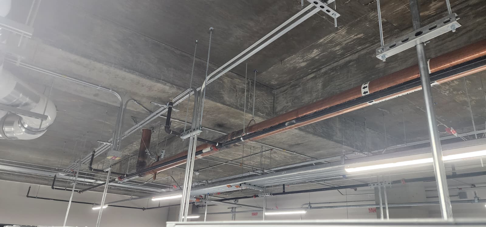 Wet sprinkler system branch lines and mains with upright sprinkler heads installed below a structural ceiling